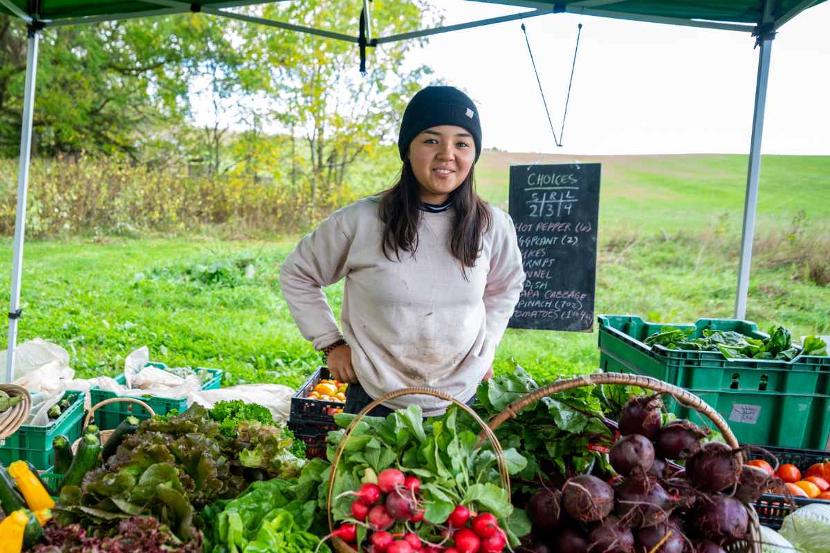 Woman standing in front of farm stand.