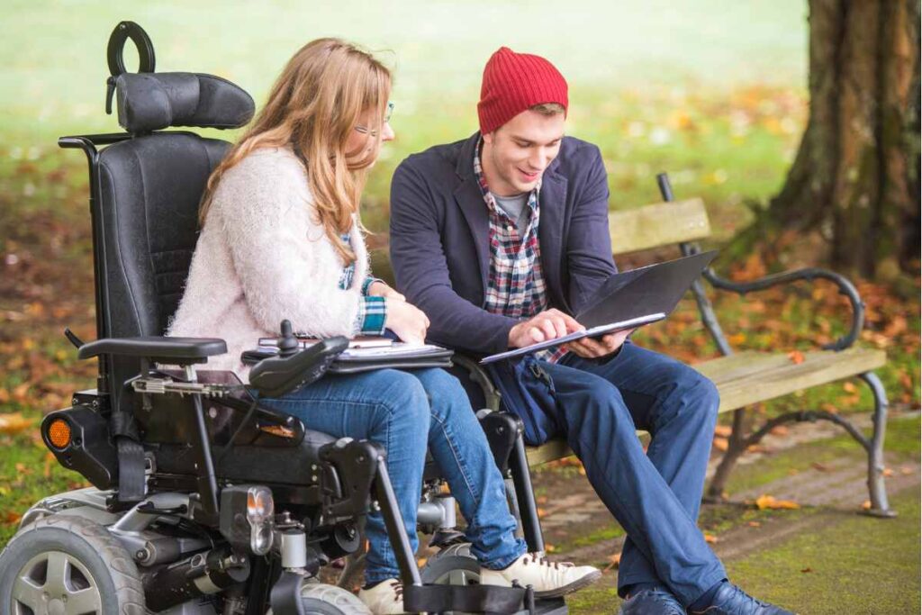 Two students discussing some information on a piece of paper. One of the students is in a wheelchair.